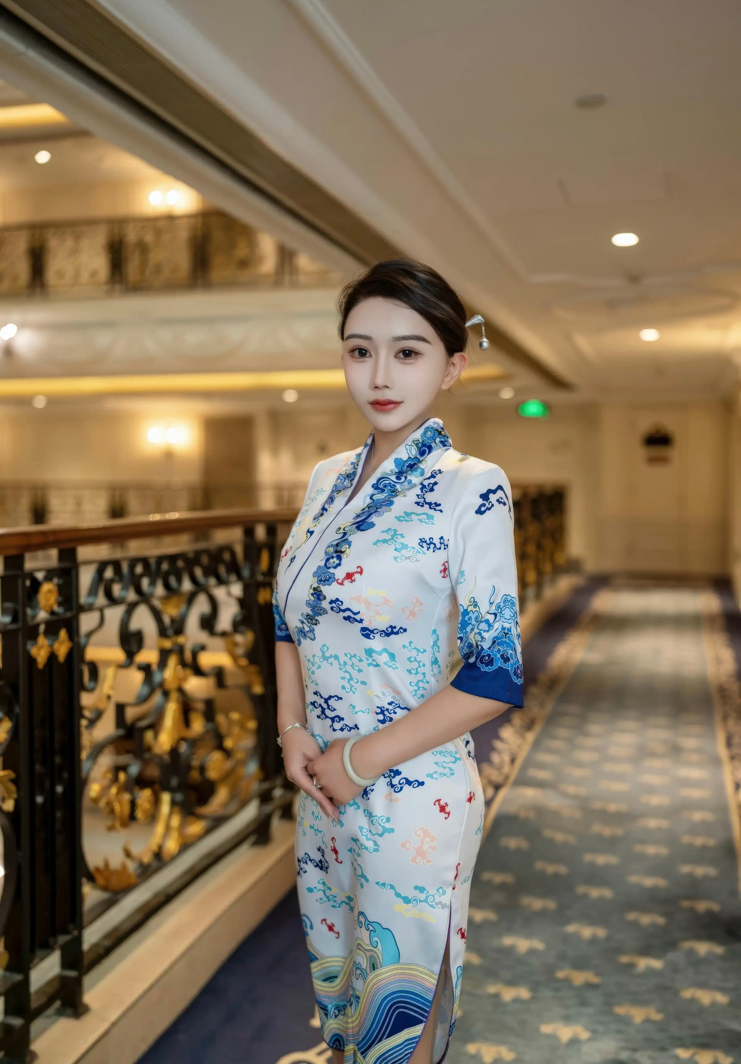 Woman in a white patterned cheongsam stands in a luxurious hotel hallway with ornate railings.